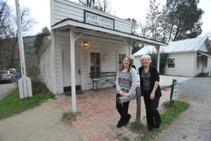 POSTAL CLERK Sabrina Parsonson, left, and Postmaster Kathy Jacques, right, stand near a hitching post in front of the Coloma Post Office Friday Feb. 6. Democrat photo by Pat Dollins